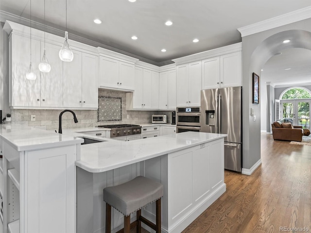 425 Steele St, Denver, CO 80206 - kitchen with appliances with stainless steel finishes, wood finished floors, a peninsula, white cabinets, and crown molding