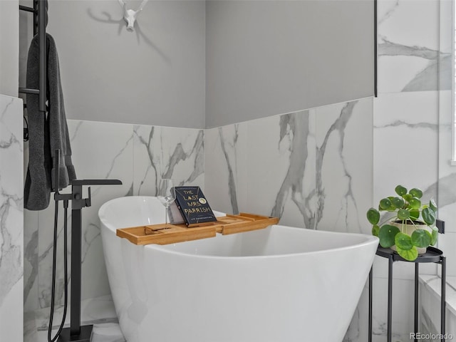 425 Steele St, Denver, CO 80206 - bathroom with marble tiled floors, tile walls, a freestanding tub, and wainscoting