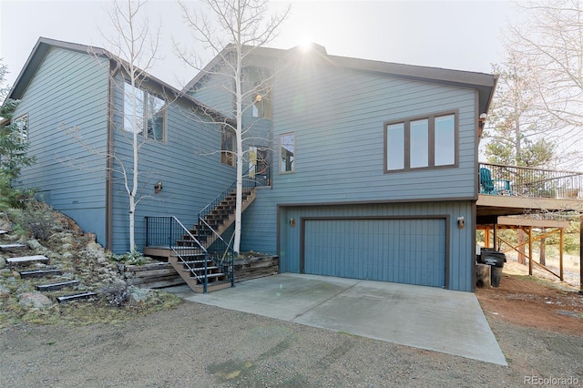rear view of house with stairs, a garage, and driveway