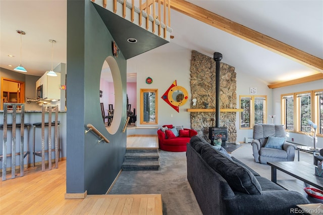 living room with wood finished floors, beam ceiling, a wood stove, high vaulted ceiling, and baseboards