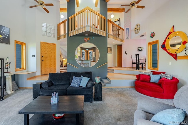 carpeted living room featuring a ceiling fan, stairway, high vaulted ceiling, and baseboards