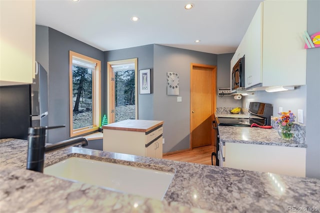kitchen featuring a sink, black appliances, recessed lighting, white cabinets, and light wood-style floors