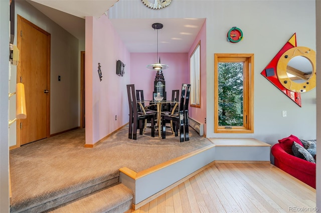 dining room featuring a baseboard heating unit, baseboards, and hardwood / wood-style floors