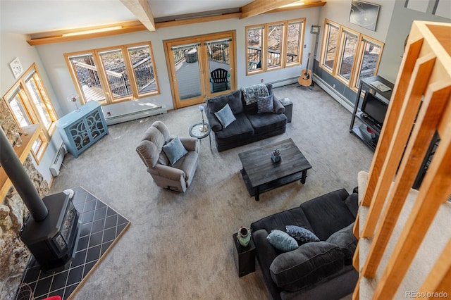 living room featuring a wood stove, beamed ceiling, a baseboard heating unit, and carpet floors