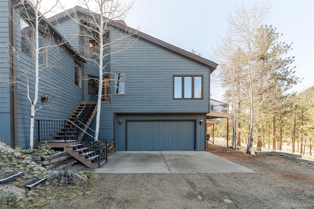view of property exterior with an attached garage, stairway, and driveway