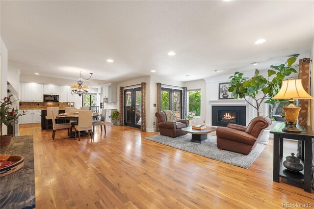 living room with plenty of natural light, light hardwood / wood-style flooring, and a notable chandelier