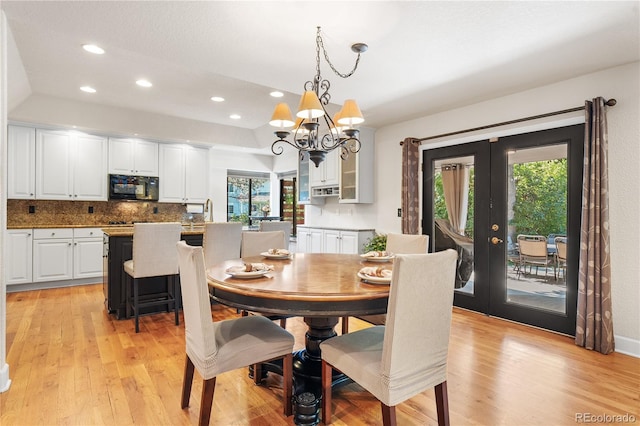 dining space with light wood-type flooring, a notable chandelier, and plenty of natural light