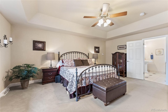 carpeted bedroom featuring ceiling fan, connected bathroom, and a raised ceiling