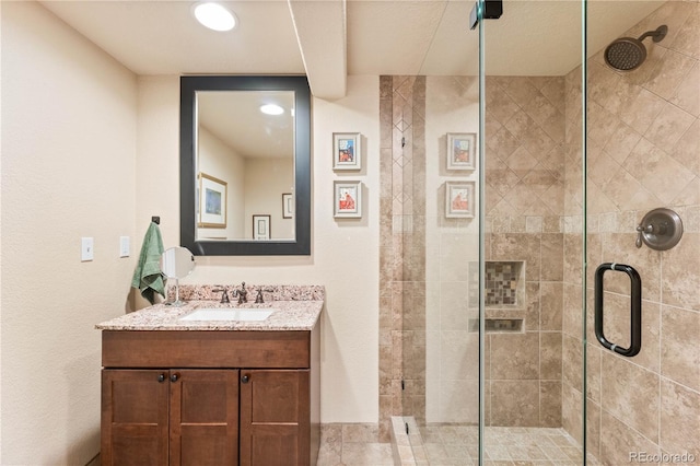 bathroom featuring a shower with shower door and vanity