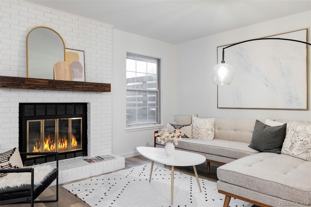 living room featuring brick wall, wood-type flooring, and a fireplace