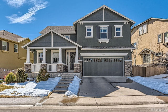 craftsman inspired home with driveway, a garage, stone siding, a porch, and stucco siding