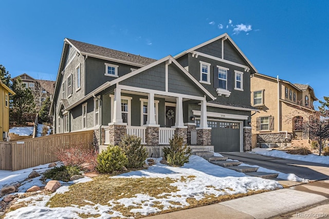 view of front of house with an attached garage, covered porch, stone siding, driveway, and stucco siding