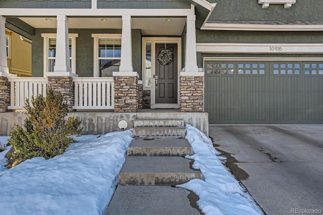 view of exterior entry featuring a garage, stone siding, driveway, and stucco siding