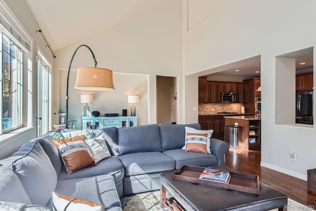 living area featuring high vaulted ceiling, baseboards, and dark wood-style flooring