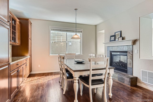 dining room with baseboards, a fireplace, visible vents, and dark wood-style flooring