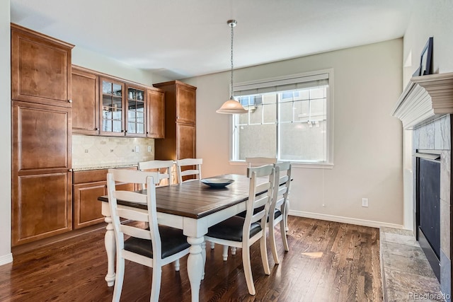 dining area with a fireplace, baseboards, and dark wood-type flooring