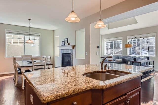 kitchen featuring a center island with sink, a tile fireplace, dark wood-style floors, open floor plan, and a sink