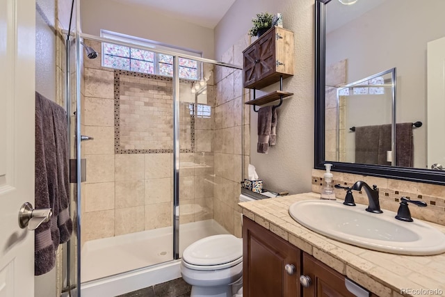 bathroom featuring toilet, a textured wall, a shower stall, and vanity