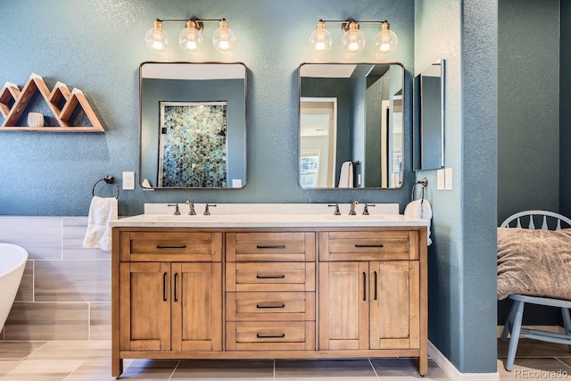 bathroom featuring a textured wall, a freestanding tub, a sink, and double vanity