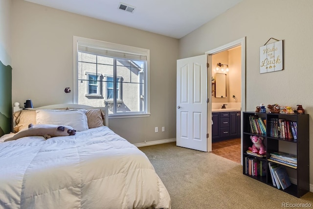 bedroom with light carpet, a sink, visible vents, baseboards, and ensuite bath