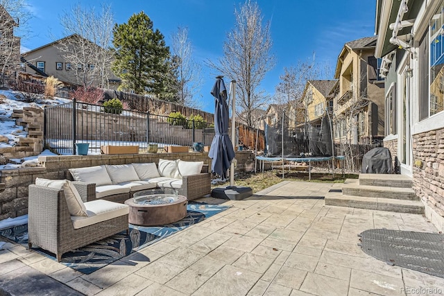 view of patio featuring entry steps, a trampoline, fence, and an outdoor living space with a fire pit