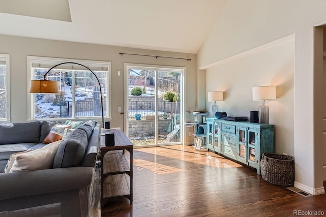 living area featuring vaulted ceiling, wood finished floors, visible vents, and baseboards