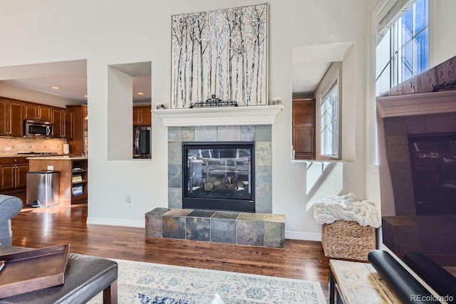 living room featuring baseboards, a tiled fireplace, and wood finished floors