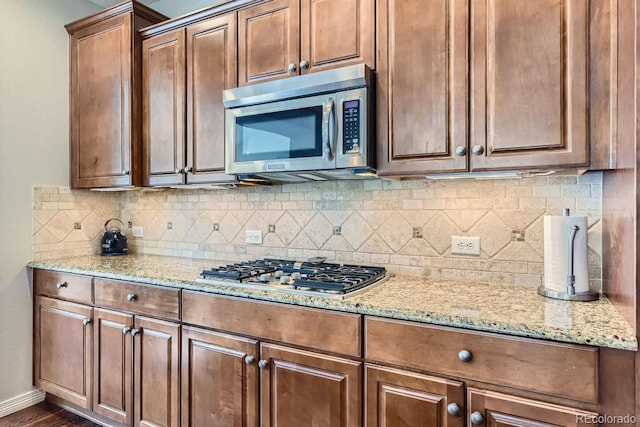 10935 Valleybrook Cir, Highlands Ranch, CO 80130 - kitchen with appliances with stainless steel finishes, tasteful backsplash, light stone countertops, and baseboards