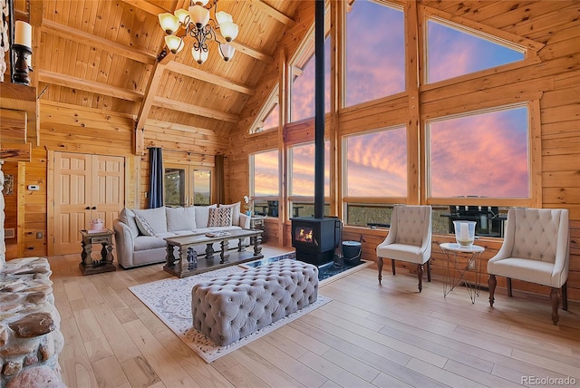 10268 Christopher Dr, Conifer, CO 80433 - living room with high vaulted ceiling, a wood ceiling with exposed beams, wooden walls, a wood stove, and a chandelier