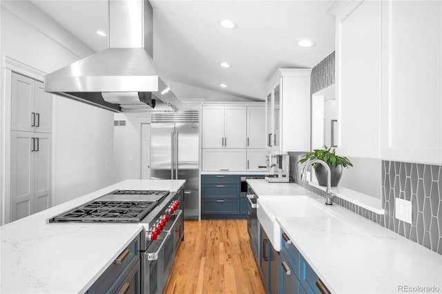 kitchen featuring blue cabinetry, island exhaust hood, white cabinetry, and high end appliances