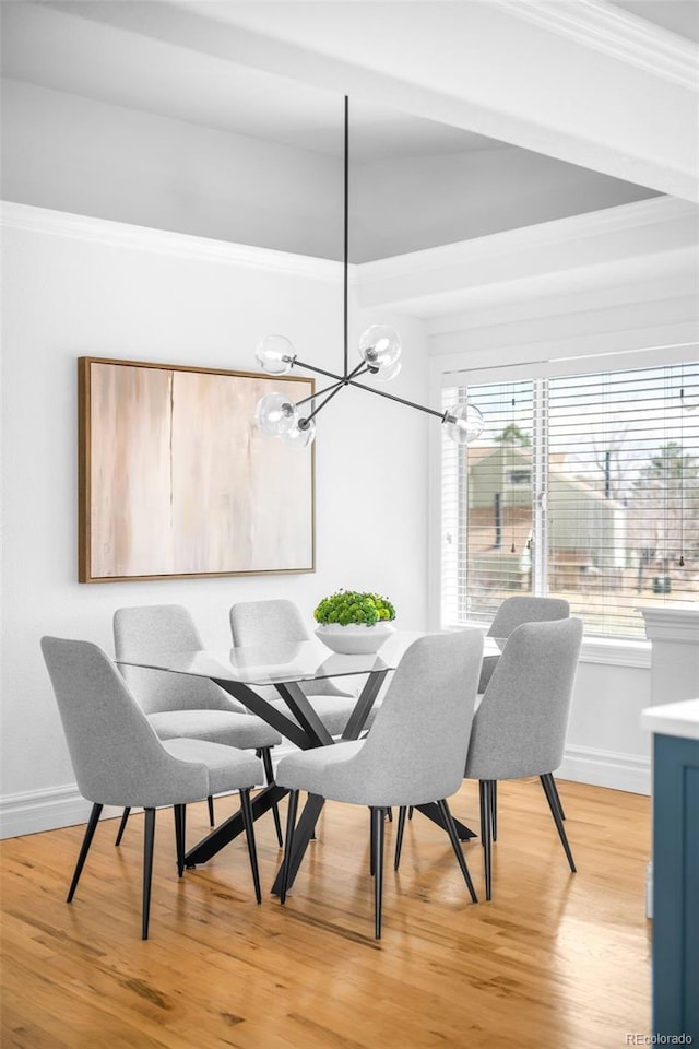 dining space with a notable chandelier, crown molding, light wood-type flooring, and baseboards