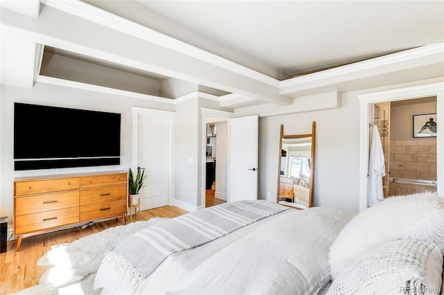 bedroom with connected bathroom and light wood finished floors