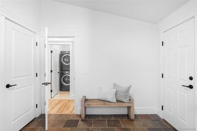 interior space featuring stacked washer and clothes dryer, stone finish floor, and baseboards