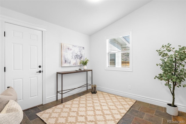 entrance foyer with lofted ceiling, stone tile flooring, and baseboards