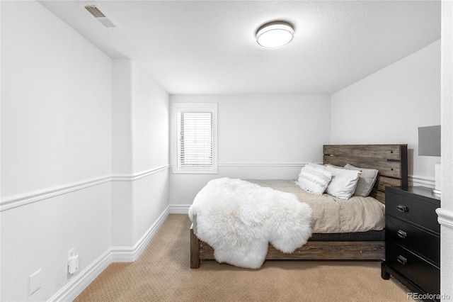 bedroom featuring baseboards, visible vents, and light colored carpet