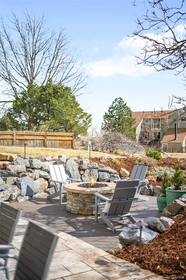 deck featuring an outdoor fire pit, a patio area, and fence