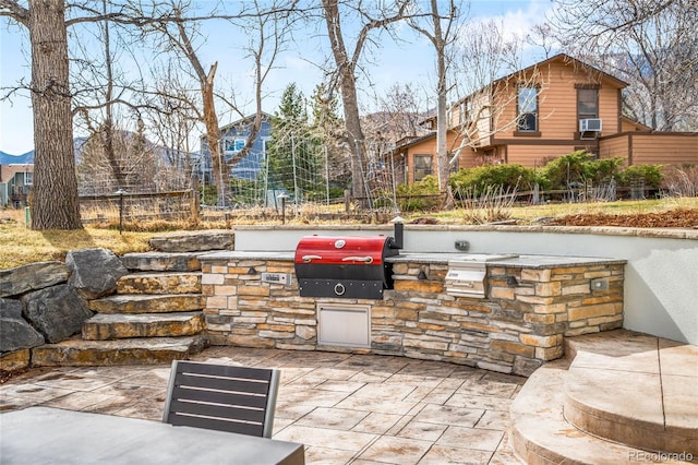 view of patio featuring fence, exterior kitchen, and area for grilling