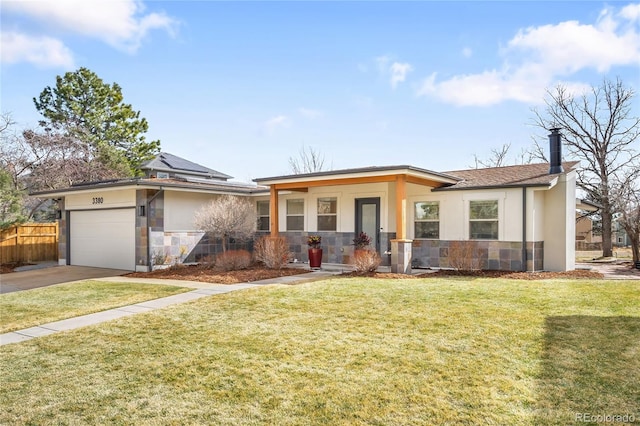 prairie-style house with a garage, solar panels, stone siding, a front lawn, and stucco siding