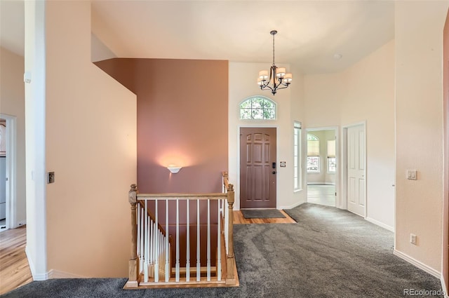 foyer featuring carpet floors, a chandelier, and a high ceiling