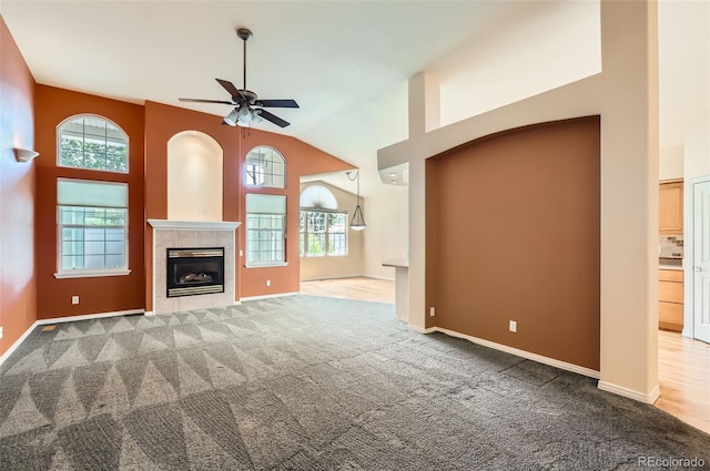 unfurnished living room with ceiling fan, carpet flooring, high vaulted ceiling, and a fireplace