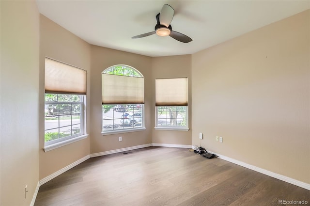 unfurnished room with healthy amount of natural light, wood finished floors, and a ceiling fan