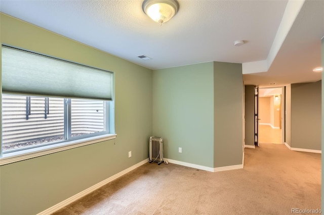 unfurnished room featuring radiator heating unit, light colored carpet, and a smoke detector