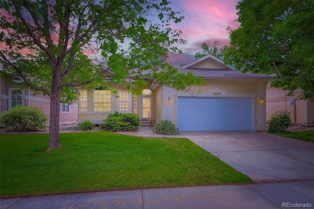 ranch-style house featuring stucco siding, a yard, concrete driveway, and a garage