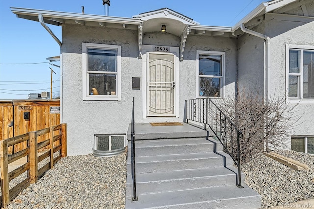 entrance to property with fence and stucco siding