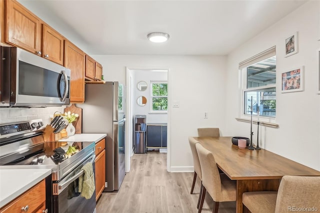 kitchen featuring light wood-type flooring, appliances with stainless steel finishes, a healthy amount of sunlight, and backsplash