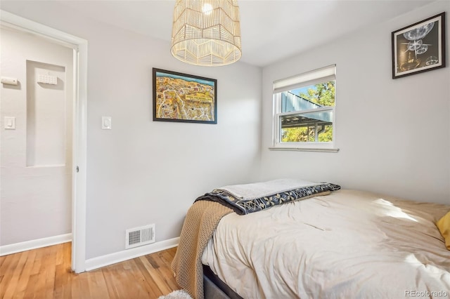 bedroom with hardwood / wood-style flooring and an inviting chandelier