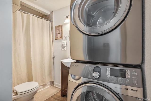 laundry room featuring stacked washer / dryer and hardwood / wood-style flooring