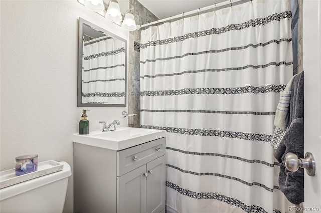 bathroom featuring toilet, walk in shower, and vanity