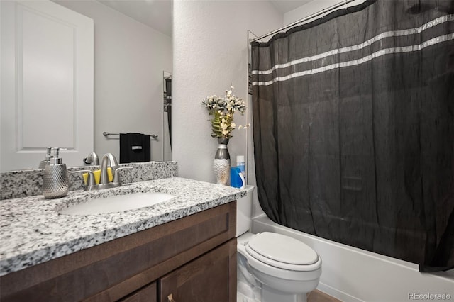 bathroom featuring vanity, toilet, a textured wall, and shower / tub combo