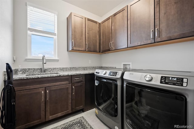 laundry area featuring cabinet space, light tile patterned flooring, washer and clothes dryer, and a sink
